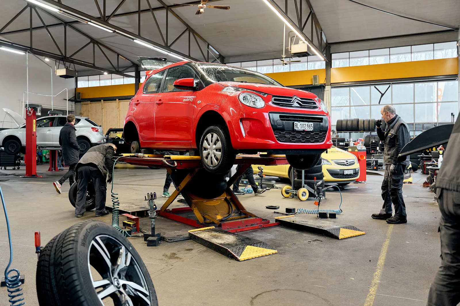Un mécanicien monte des pneus sur une voiture Mobility.