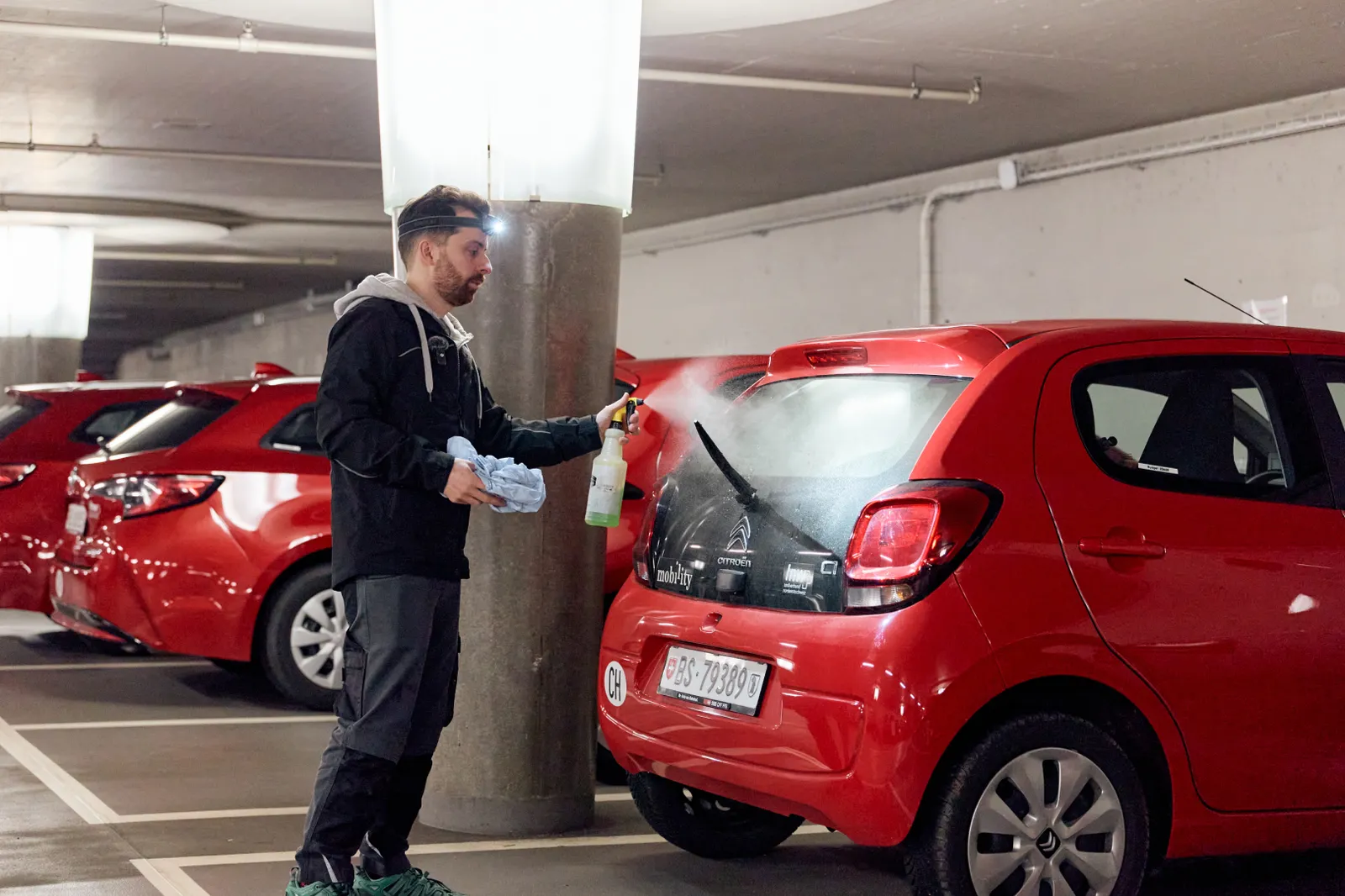Un collaborateur du ServiceMobil examine une voiture dans un parking souterrain.
